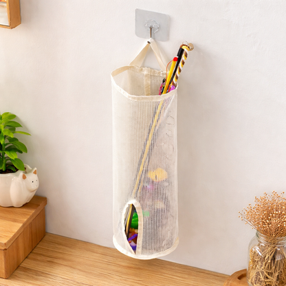 Mesh storage bag hanging on a hook with cat toys inside, next to a plant and decorative items.
