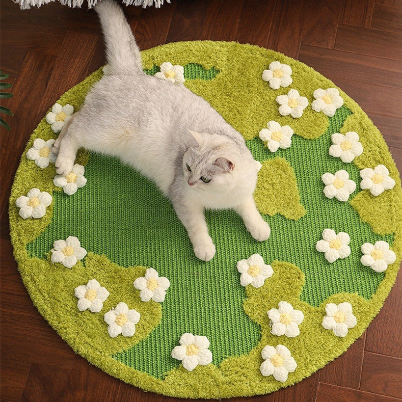 Cat lying on a green round rug with white floral patterns on a wooden floor.