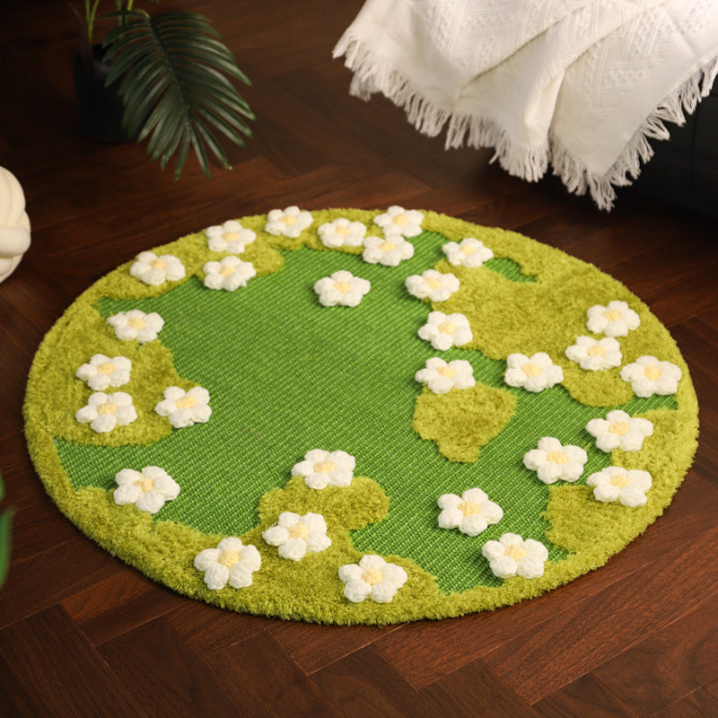 Round green rug with white floral patterns on a wooden floor.