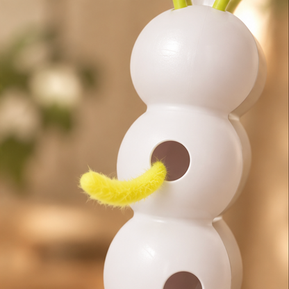 Close-up of a white caterpillar-shaped interactive cat toy with green antennae and a fuzzy yellow tail extending from a circular opening.