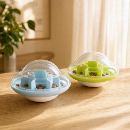 UFO Treat Tumbler, one light blue and one lime green, filled with kibble on a wooden table in a softly lit room.